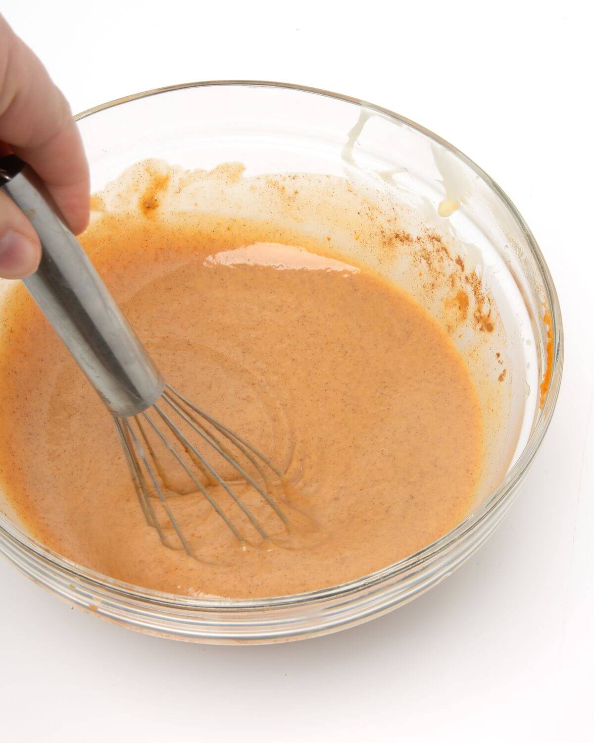 pumpkin spice sauce ingredients mixed in glass bowl with whisk