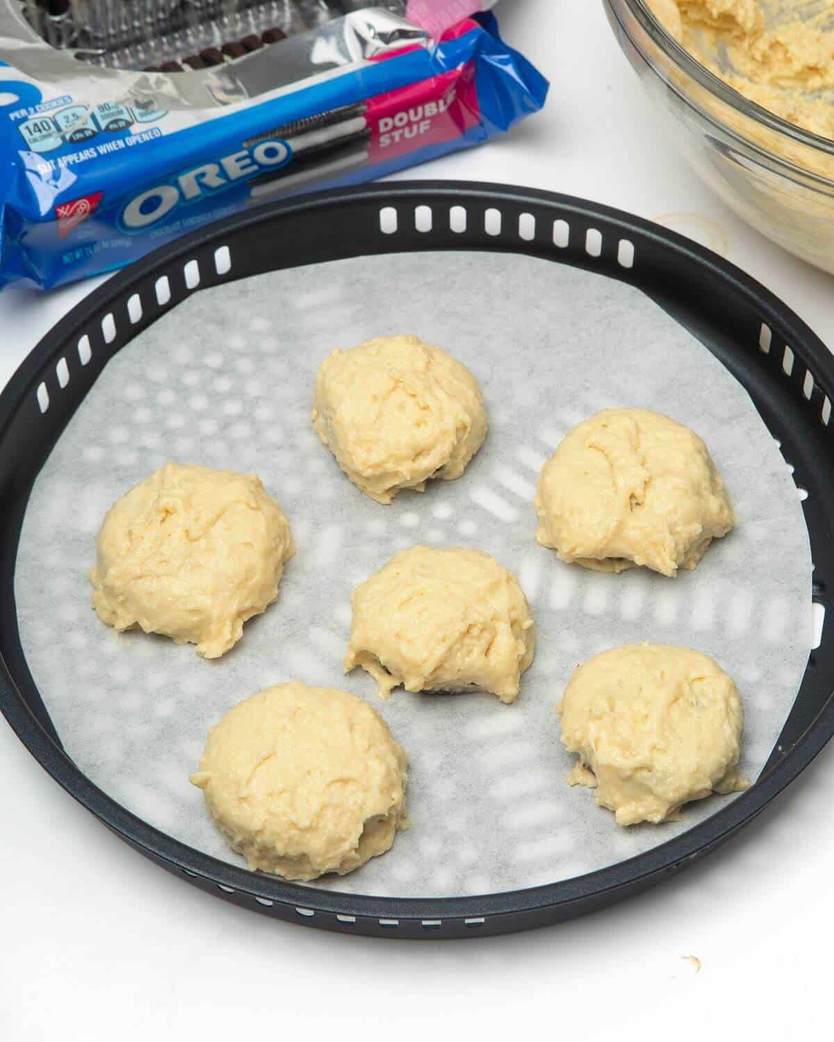 oreos dipped in batter on air fryer tray lined with parchment paper