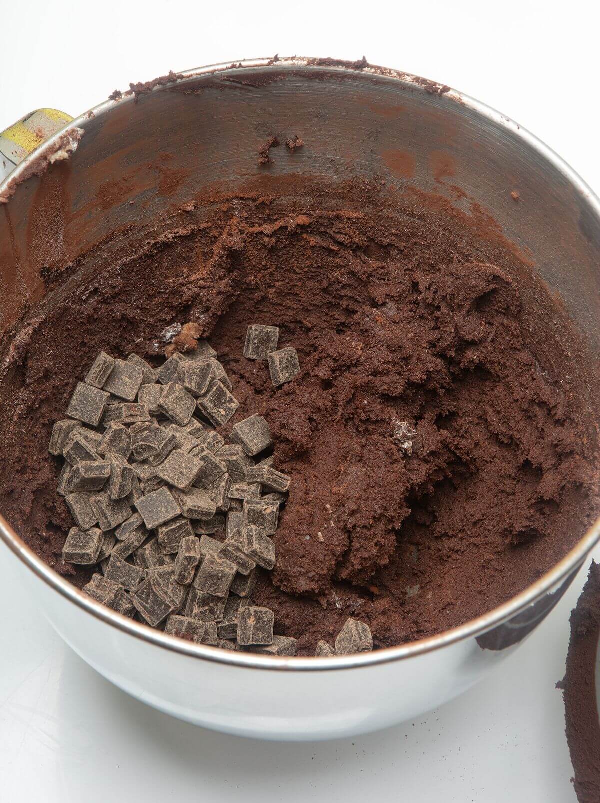 Dark chocolate cookie dough in mixing bowl with chocolate chunks.