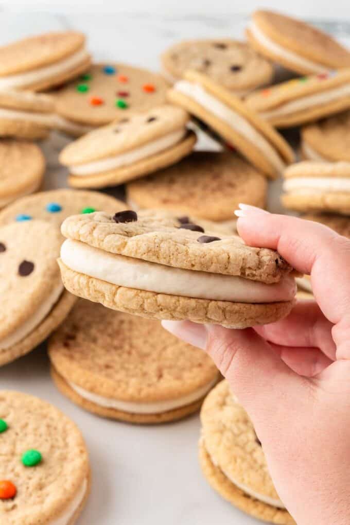 Holding a chocolate chip cookie sandwich.