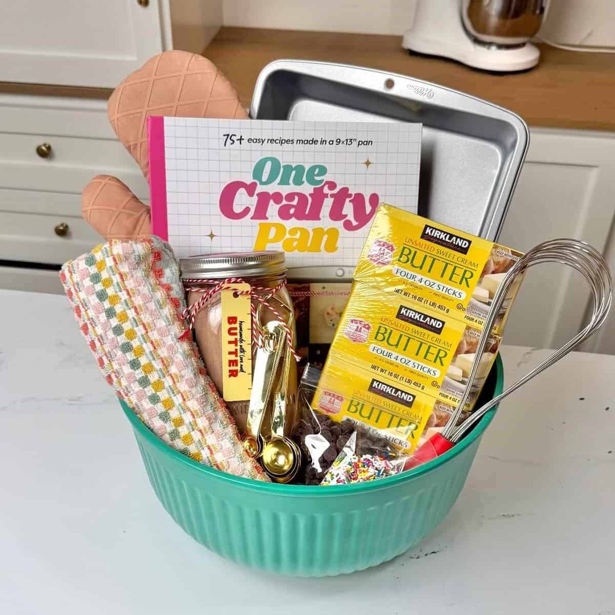 Multiple mason jars filled with homemade brownie mix labeled as gifts with a gift basket and One Crafty Pan cookbook