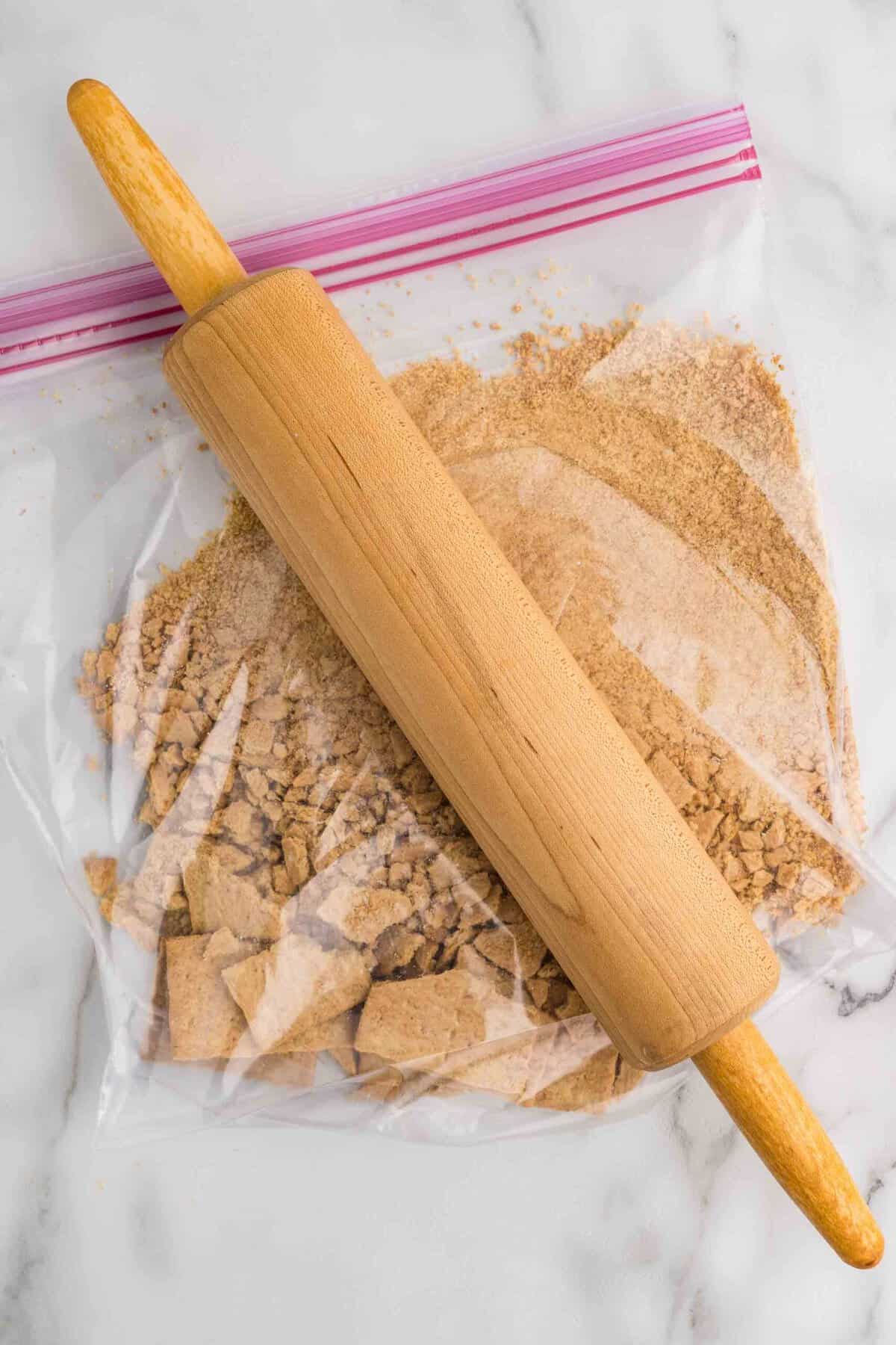 Step 1 - Crushing graham crackers in a zip-top bag with a rolling pin for the cookie dough crumb mix-in