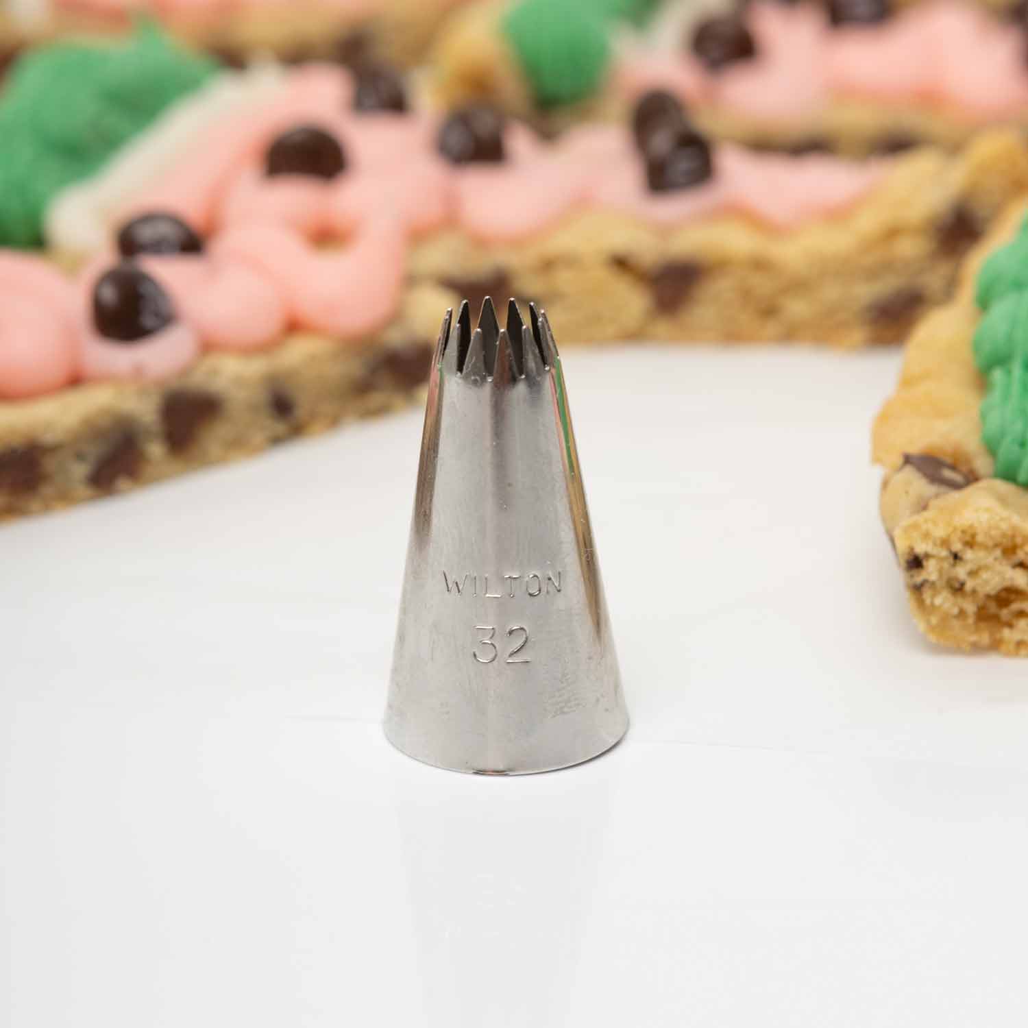 Wilton 32 star piping tip in front of watermelon cookie cake slices with pink frosting and M&M seeds