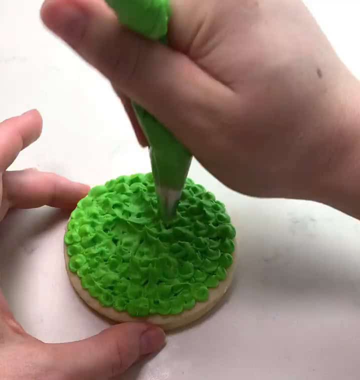 Round sugar cookie fully covered in fuzzy green buttercream