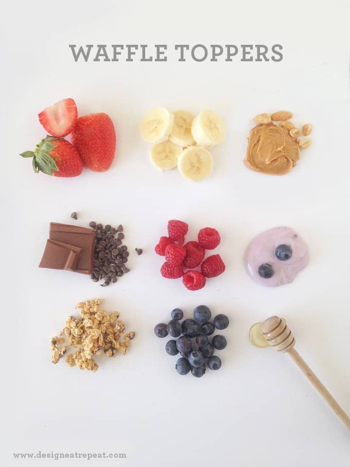Overhead picture of waffle bar with waffle toppings. Blueberries, raspberries, peanut butter, bananas, and more.