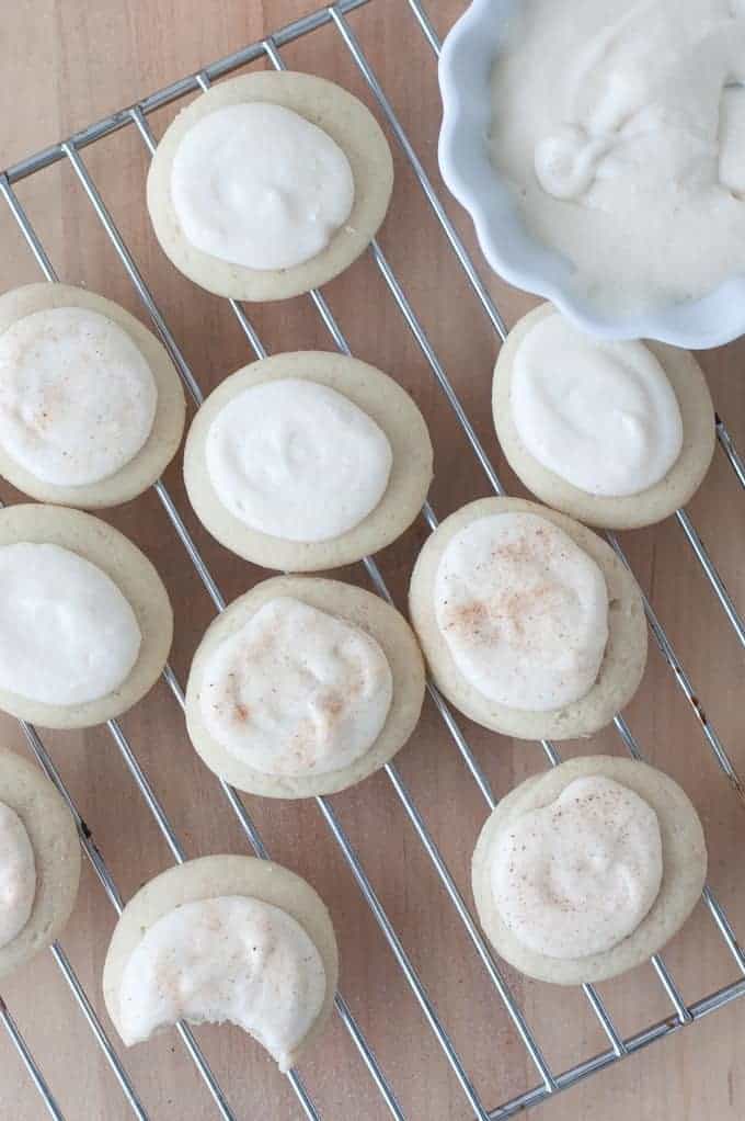Scalloped bowl of Cream Cheese Maple Glaze with wire tray of sugar cookies