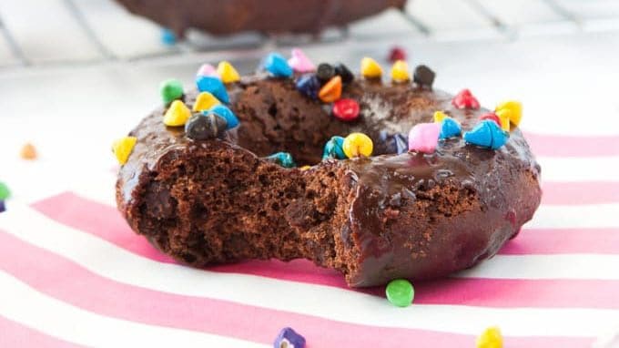 Cosmic Triple Chocolate Cake Donuts on wire rack with rainbow sprinkles