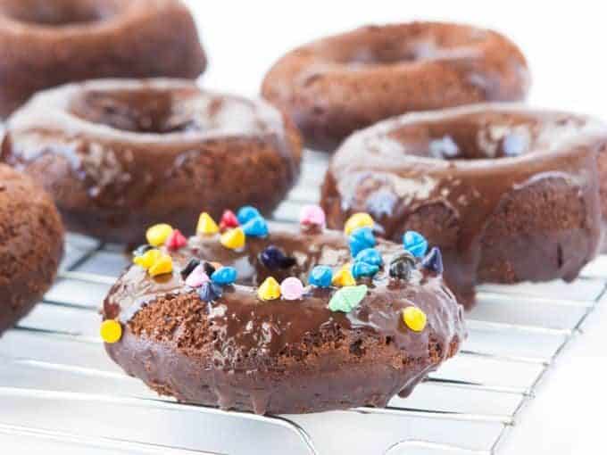 Cosmic Triple Chocolate Cake Donuts on wire rack with rainbow sprinkles