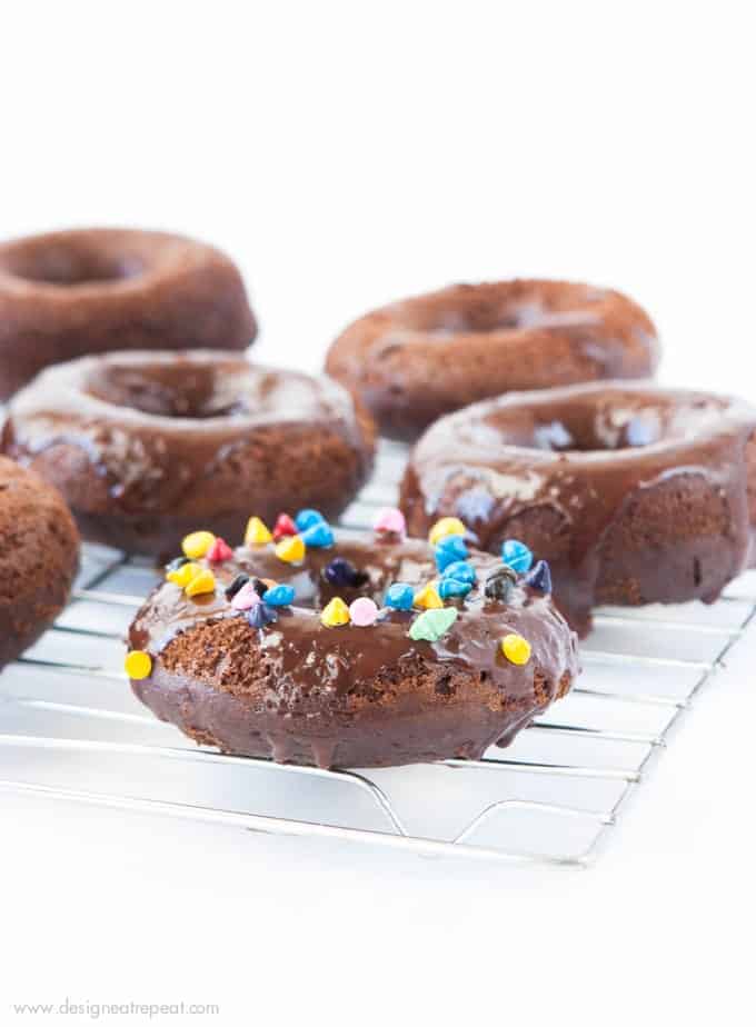 Cosmic Triple Chocolate Cake Donuts on wire rack with rainbow sprinkles