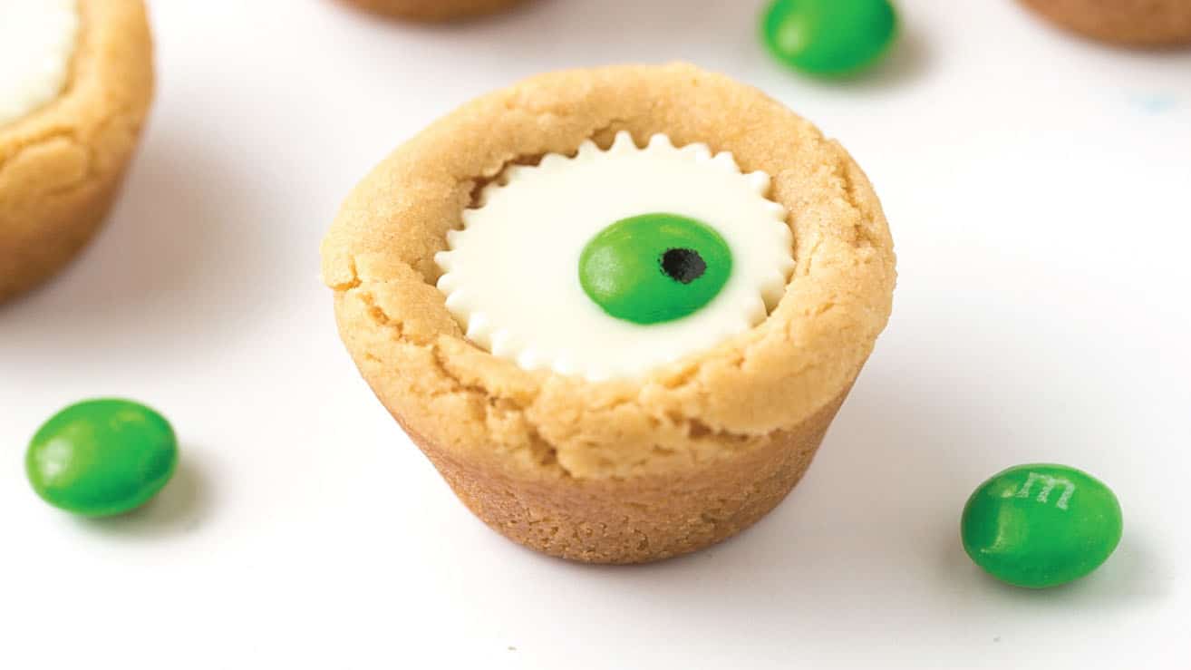 Mini white peanut butter cup cookies with green M&M in center to look like Halloween eyeball.