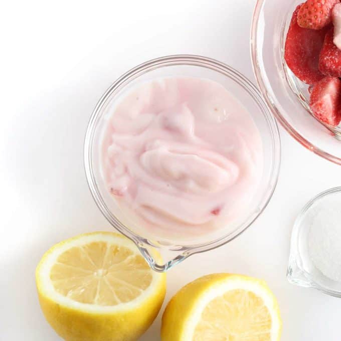 Bowl of raspberry yogurt with lemon and strawberries