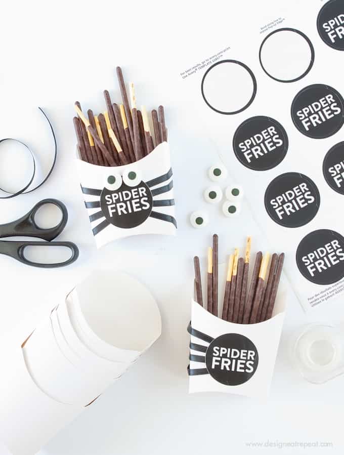 Make these DIY Spider Fry Boxes with paper fry boxes, pocky sticks, and free printable sticker labels! Great Halloween Treat Idea by @DesignEatRepeat blog!