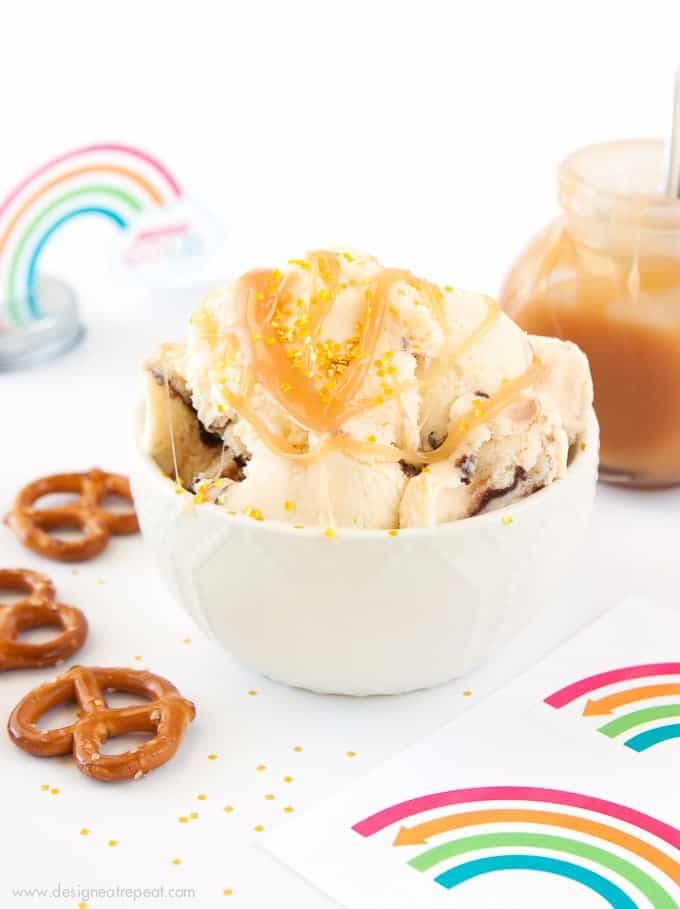 Bowl of ice cream with caramel sauce drizzles, pretzels, and rainbow printables.