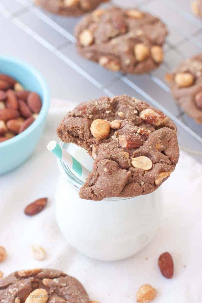  Milk Chocolate Peanut Butter & Almond Cookie with bite taken out, sitting on top of milk jar with blue straw.
