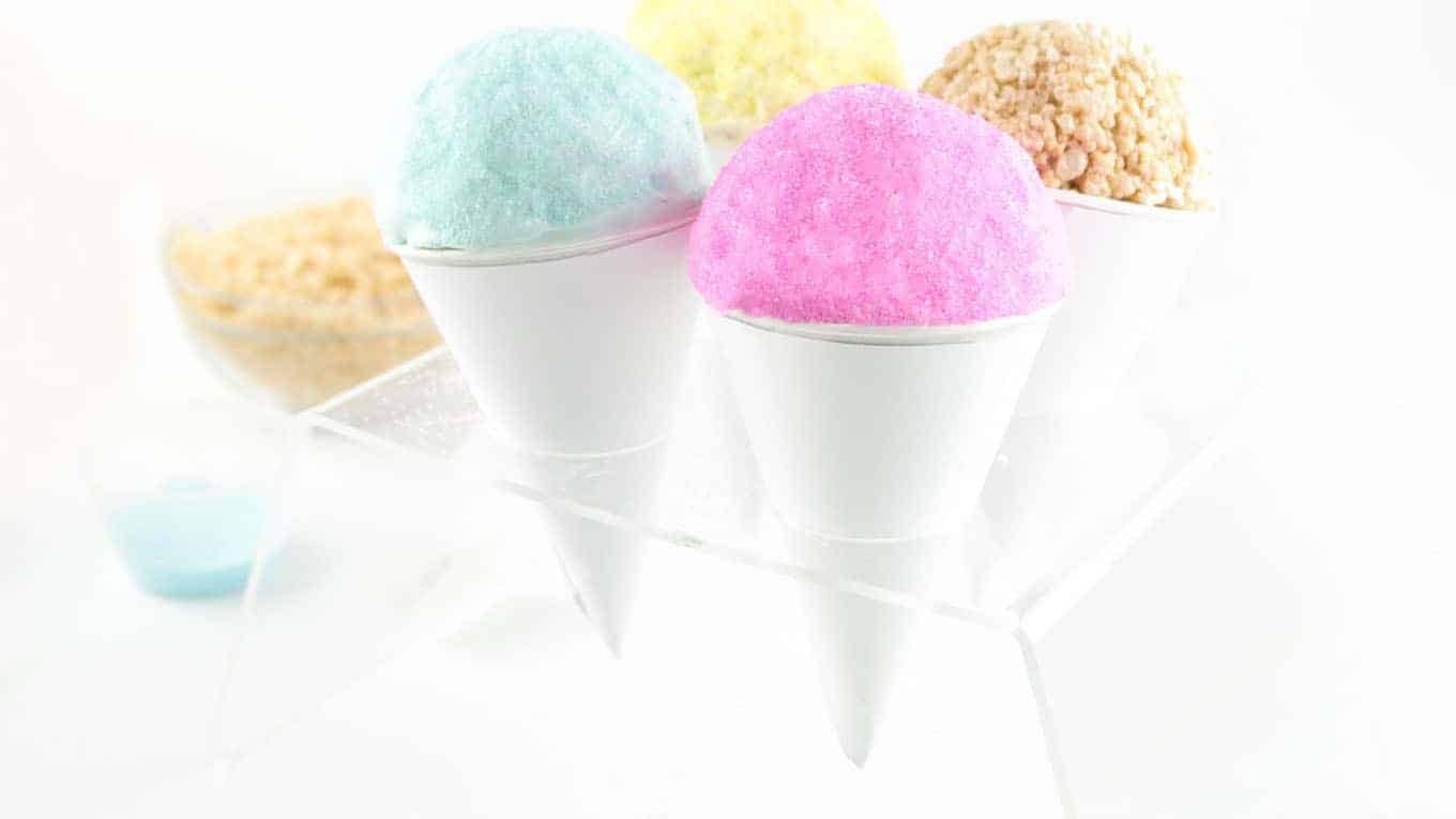 Rice Krispies in ice cream cone holder with colored chocolate and sanding sugar on top.