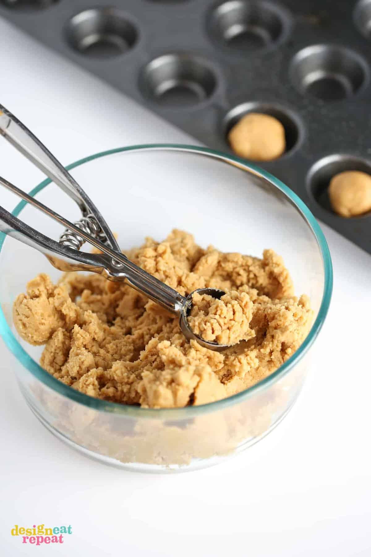 Glass bowl of Peanut butter cookie dough with cookie scoop