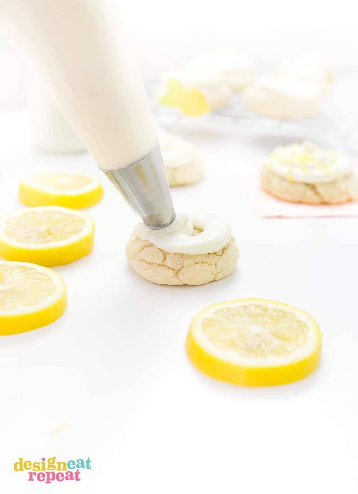 Piping bag and tip piping cream cheese frosting onto thick lemon sugar cookie.