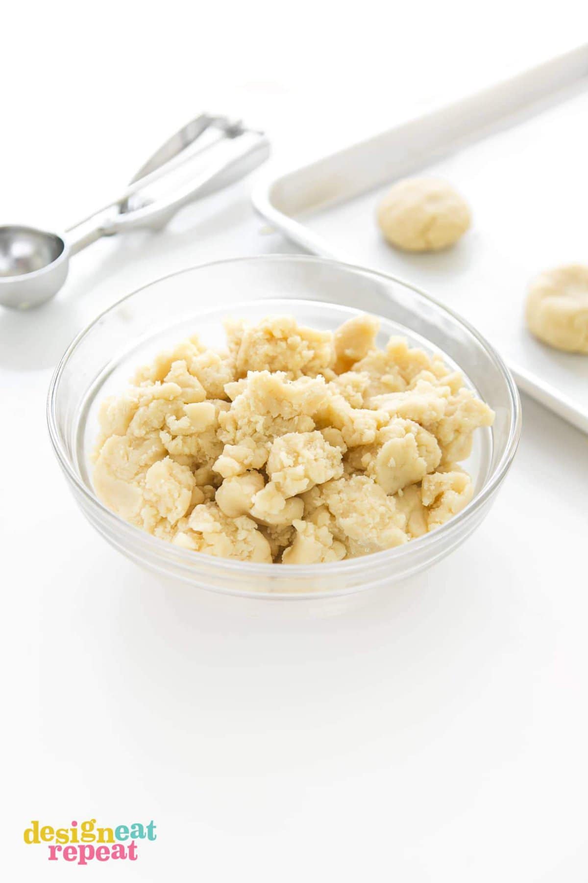 Bowl of raw thick lemon sugar cookie dough being scooped onto baking tray.