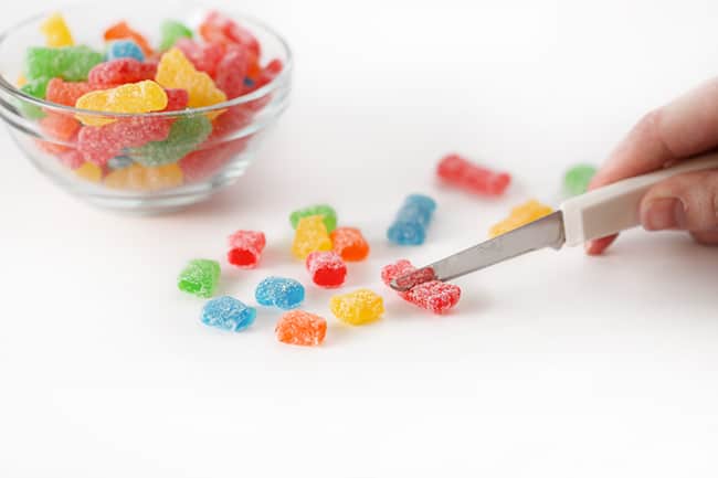 Cutting sour patch kids candy in half with a knife to make sour patch kids cookies.