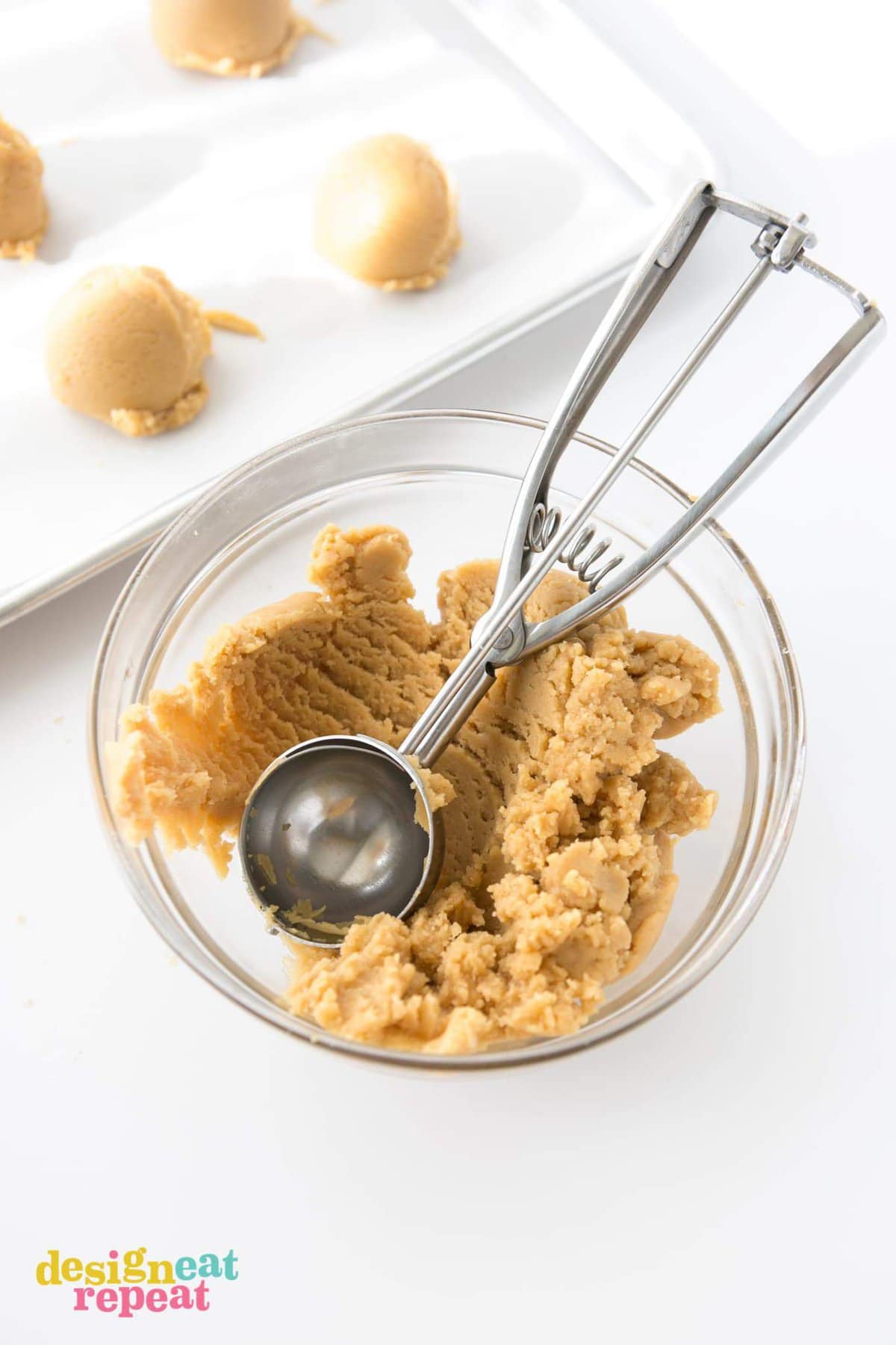 Metal scoop in bowl of peanut butter cookie dough.