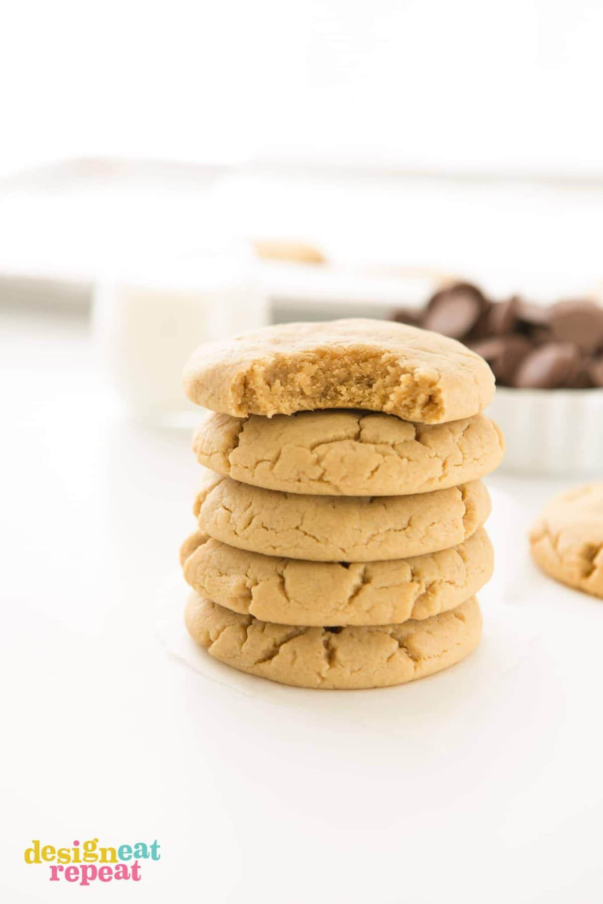 Stack of peanut butter cookies with bite taken out of top cookie.