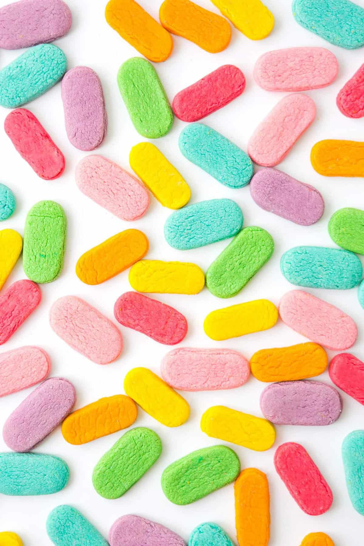 Variety of rainbow sprinkle shaped sugar cookies on white background.