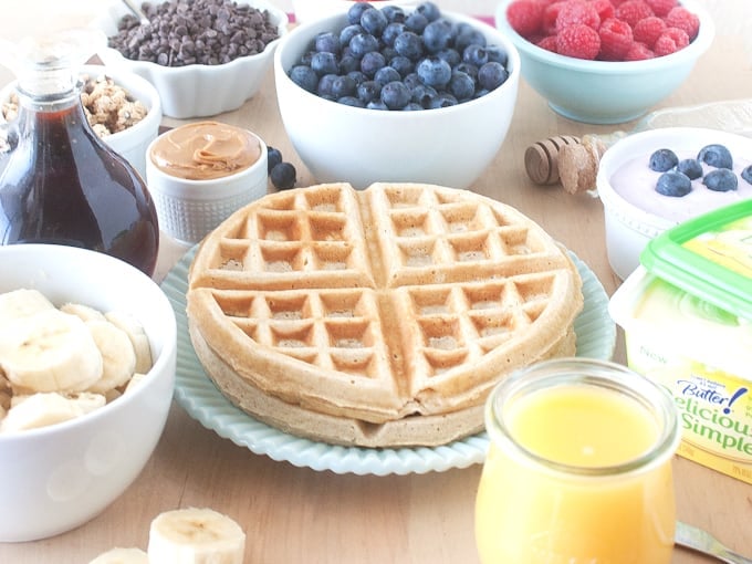 Plate of whole wheat waffles with bowls of waffle toppings 