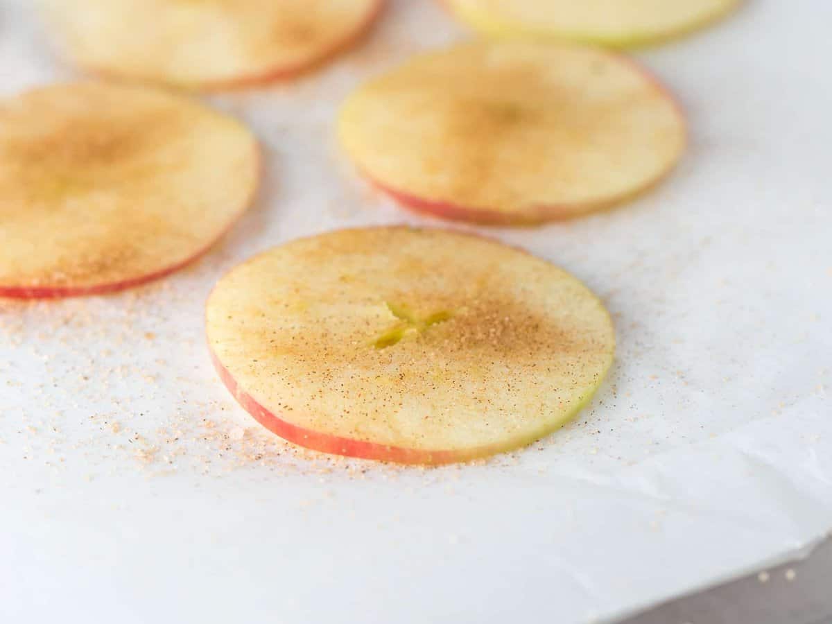 Cinnamon sugar on top of apple slice for apple chips on baking tray.
