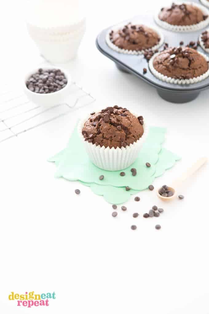 Jumbo Double Chocolate Zucchini Muffin on mint scalloped napkin, with more muffins in cupcake tin in the background.