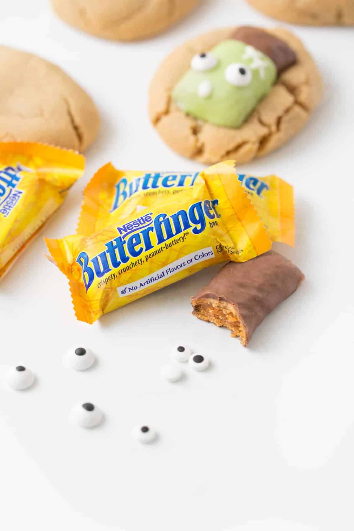 Close of shot of Butterfinger fun size candy bars with one bite of unwrapped candy bar. 
