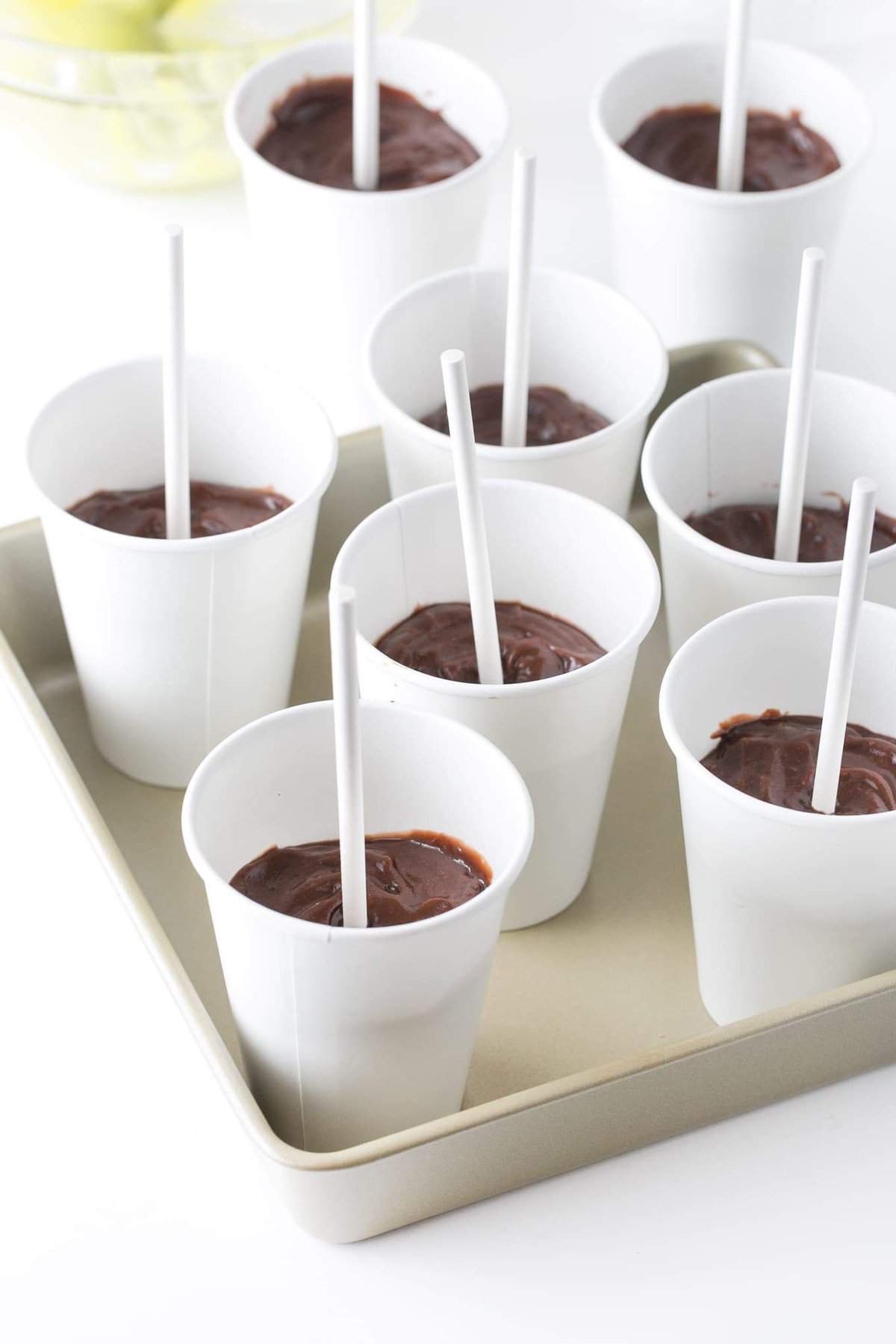 Paper cups filled with chocolate pudding, ready to go into freezer.