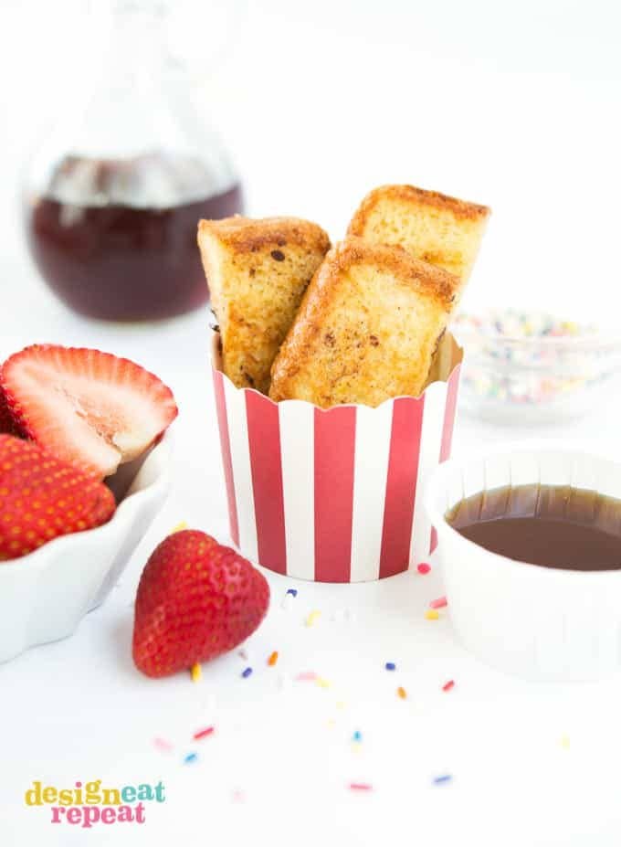 Striped red cup of homemade french toast sticks with strawberries and syrup