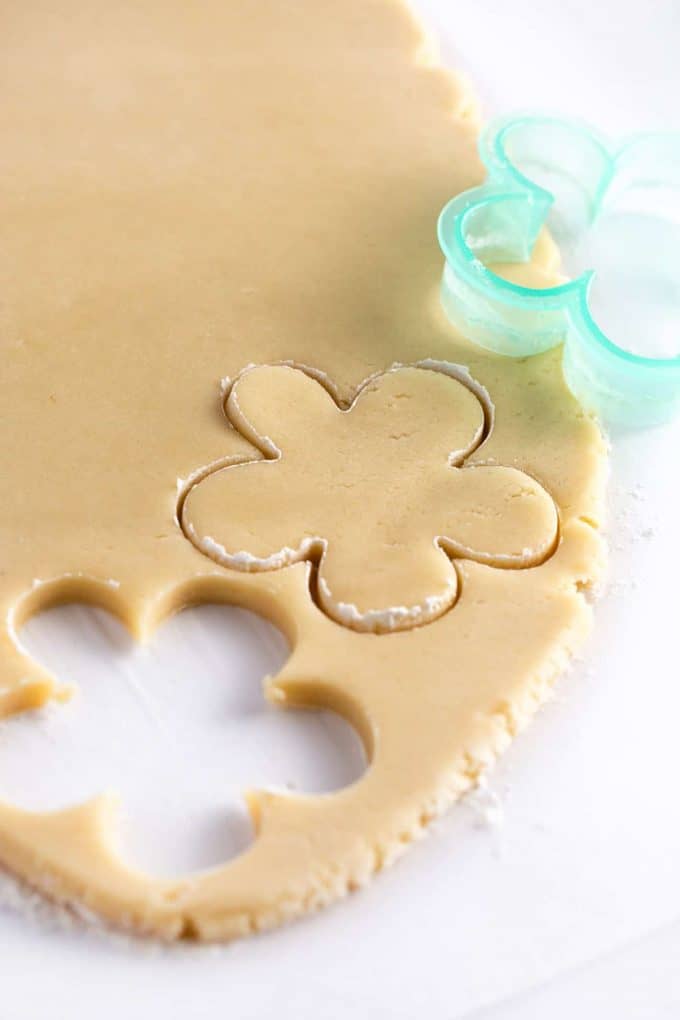 Sugar cookie dough being cut with flower cookie cutter