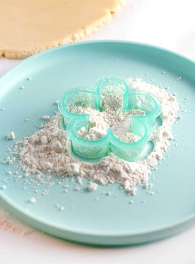 Flower cookie cutter being dipped in flour to prevent sticking