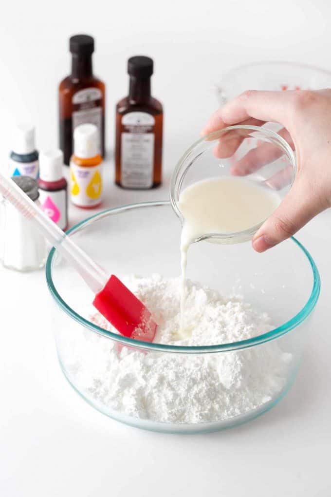 Pouring milk into bowl of powdered sugar to make powdered sugar icing for cookies