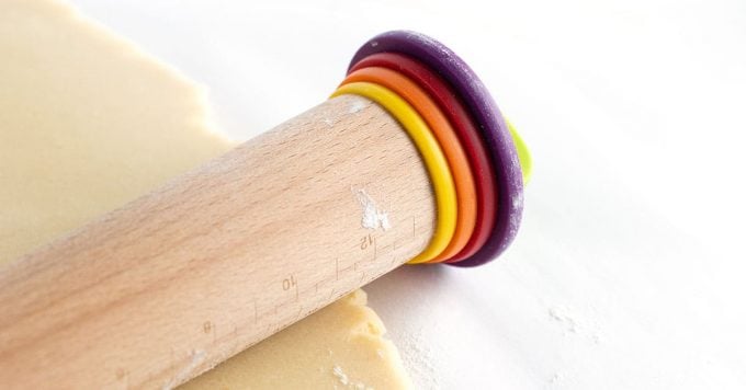 Wooden rolling pin rolling out sugar cookie dough