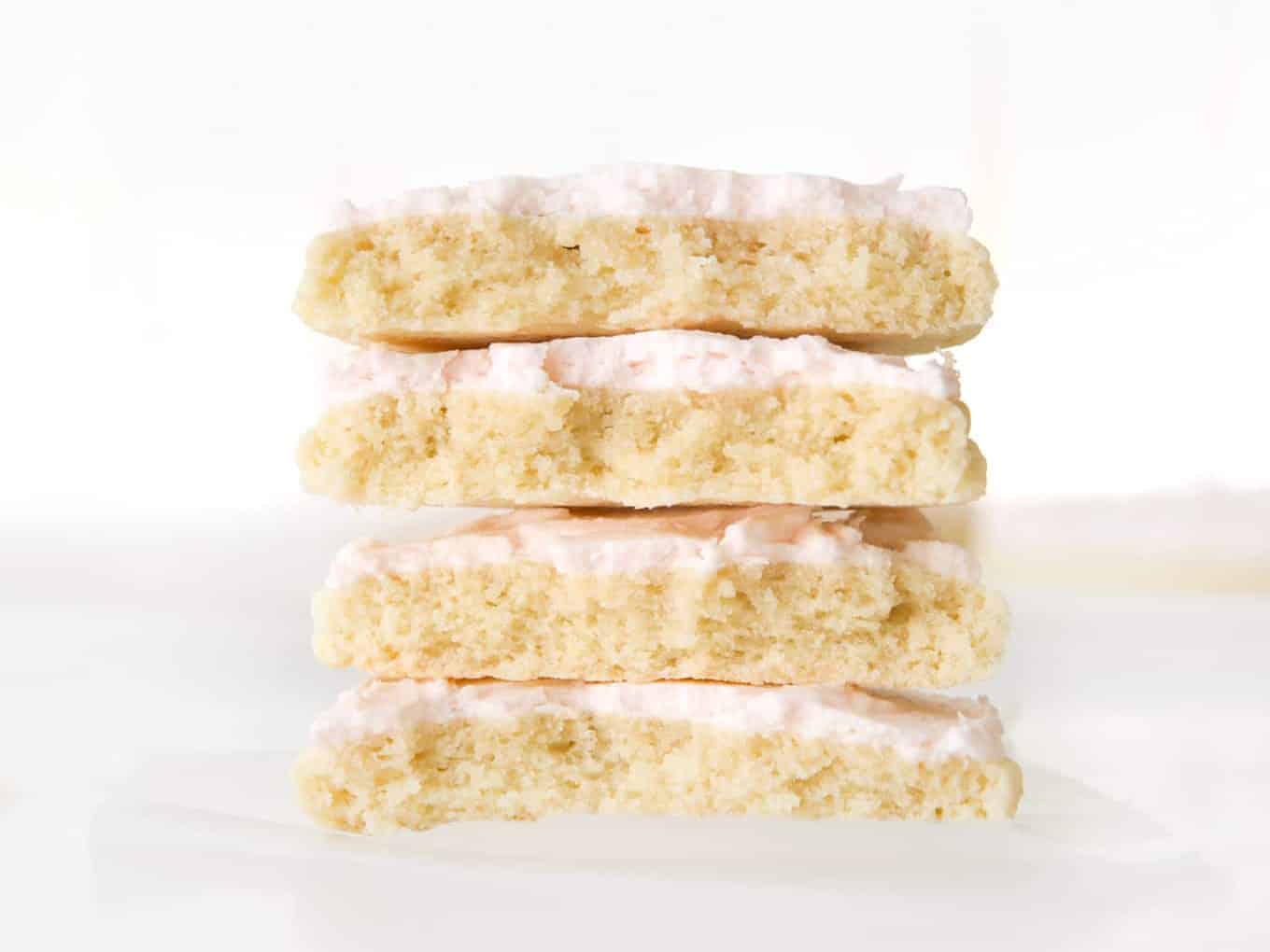 Stack of two large sugar cookies with pink frosting, cut in half.