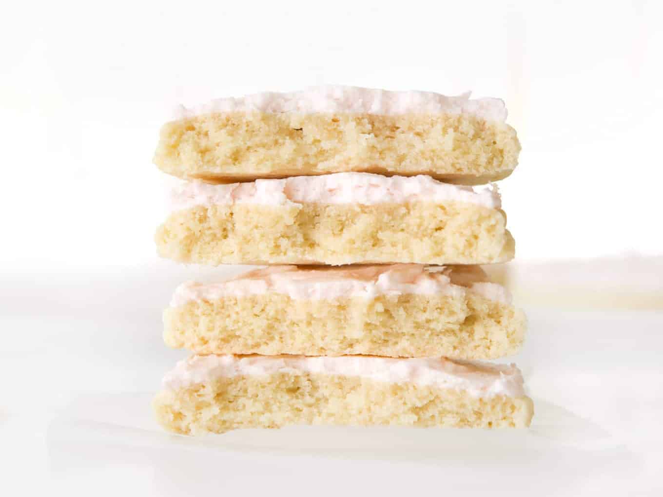 Stack of two large sugar cookies with pink frosting, cut in half.