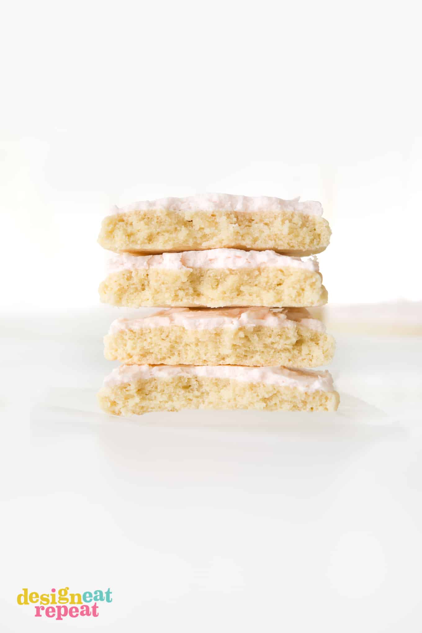 Stack of four large sugar cookies with pink frosting, cut in half.