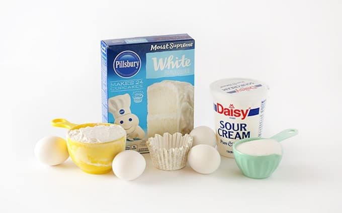 ingredients for white cake mix, includes pillsbury white boxed cake mix, sour cream, eggs, sugar, flour, and cupcake liner